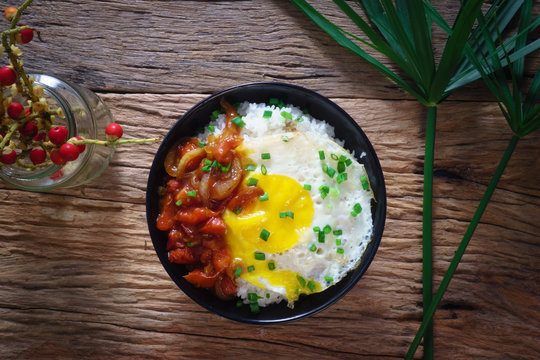 Rice with fried egg and tomato sauce on table vintage wooden sur