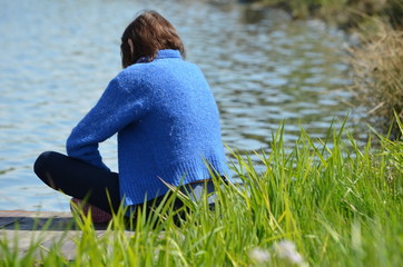 Młoda kobieta zamyślona nad brzegiem stawu/A young woman sitting pensive by the pond - obrazy, fototapety, plakaty