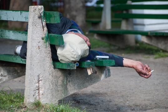 A homeless man lying on a bench