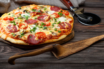 Homemade pizza on a rustic table. Wooden pizza server.