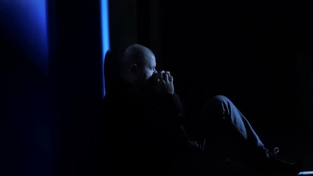 Man squatting in a corner praying in twilight