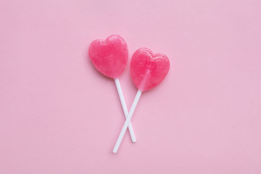 two Pink Valentine's day heart shape lollipop candy on empty pas