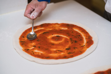Fototapeta na wymiar Pizza making in a restaurant, putting tomato sauce 