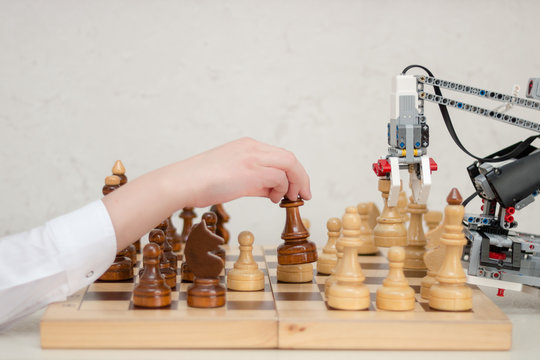 Robot arm play chess with teenager. Concept. STEM education. E-learning. 