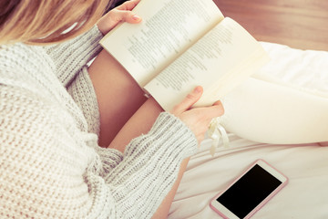 Girl enjoy eading book beside mobile wit black screen