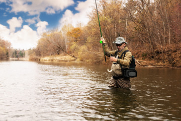 Fisherman holding a grayling caught in river