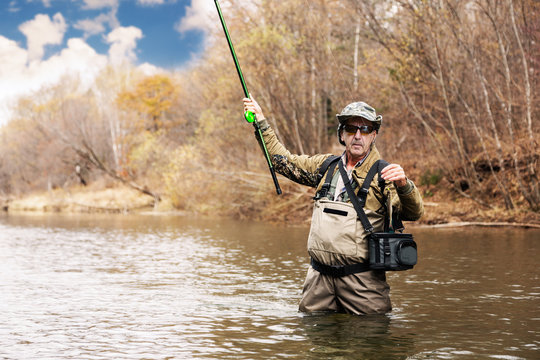 Fisherman holding a grayling caught in river