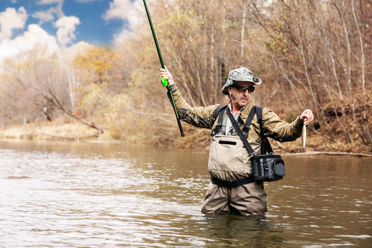Fisherman holding a grayling caught in river