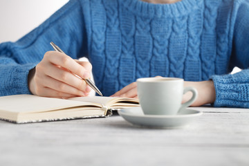 Woman write in notebook and drink coffee