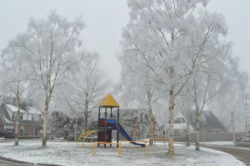 Foto auf Leinwand gekleurd speeltoestel in een winters parkje met berijpte bomen © henkbouwers