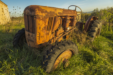 Abandoned red old rusty tractor in a field