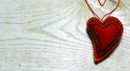 Handmade felt heart decorated with beads on wooden background. Concept with big copyspase for hand crafts or DIY illustration.