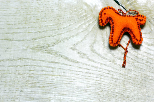 Handmade felt red color horse toy on wooden background. Concept with big copyspase for hand crafts or DIY illustration.