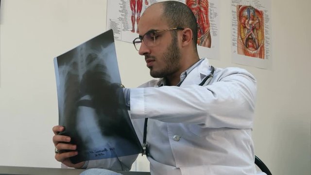 Concentrated young male doctor examining chest xray image
