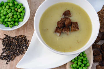 Green pea soup in a bowl with bread and sour cream