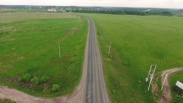 Flying over country road passing through the green meadows in Moscow countryside. Russia
