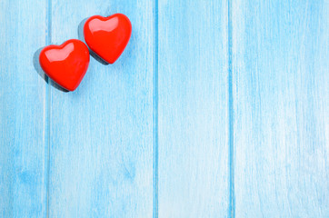 Couple of glossy red hearts for Valentine's day on blue wooden table