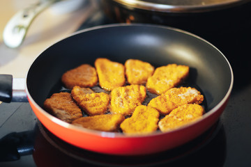 Cooking tasty chicken nuggets fried in frying-pan on home kitchen. Semifinished 