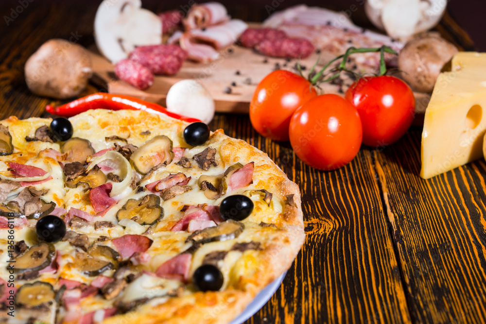 Wall mural Close up of tasty pizza, tomatoes, mushrooms and cutting board w