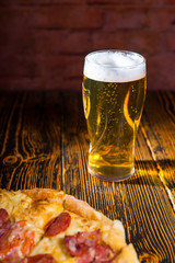 Pizza on wooden table near a glass of beer