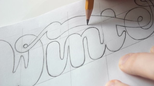 Lettering or logo creating with a pencil on white paper. Handlettering design creation process. Designer drawing letters with pen. Sketch artwork with liner marker. Calligraphy work.