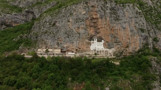 Camera flying toward to front of monastery of Ostrog in the rock of Ostroska Greda, Montenegro. Aerial view
