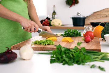 Close up of  woman's hands cooking in the kitchen. Housewife slicing ​​fresh salad. Vegetarian and healthily cooking concept