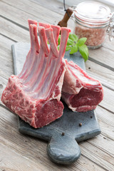 Fresh lamb ribs on the cutting board. Raw meat with basil. Rustic style.
