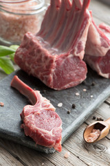 Fresh lamb ribs on the cutting board. Raw meat with basil. Rustic style.