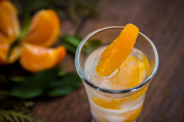 Glass with fresh juicy ripe Mandarins Tangerines, ice. Copy space and Closeup on dark background. Top view