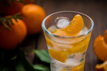 Glass with fresh juicy ripe Mandarins Tangerines, ice. Copy space and Closeup on dark background. Top view