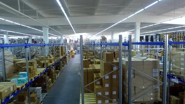 Camera moves past shelves with cardboard boxes in storage warehouse HD video. Logistics stock indoor interior
