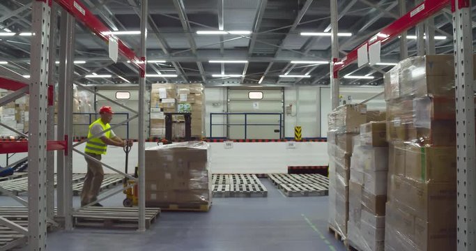 Warehouse worker transports boxes on trolley loader 4k video. Delivery man rolling hand truck platform and pulling cargo, walking at storage