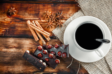 coffee cup and beans, cinnamon sticks, nuts and chocolate on woo