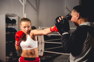 Woman boxer hitting training mitts held by her coach
