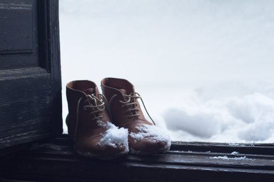 vintage leather shoes covered in snow by the door