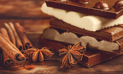 Broken chocolate bar and spices on wooden table. Selective focus