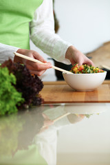 Closeup of human hands cooking vegetables salad in kitchen on the glassr table with reflection. Healthy meal and vegetarian concept