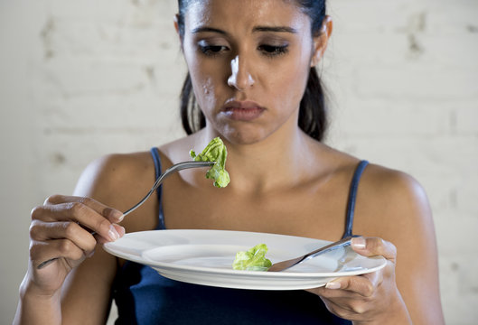 young woman holding dish with ridiculous lettuce as her food symbol of crazy diet nutrition disorder