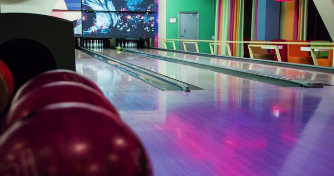 Woman playing bowling game and throwing ball to lane 4k leisure video. Girl rolling ball on alley back view. Hobby and competitions