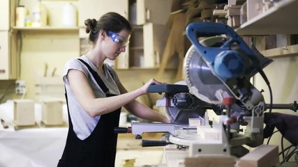 A woman is working with wood using a special machine in a studio.