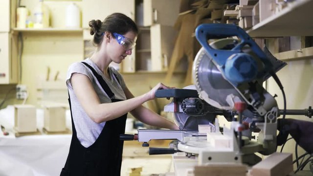 A woman is working with wood using a special machine in a studio.