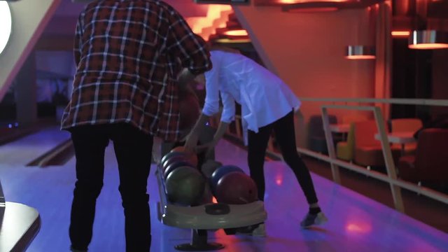 Friends playing and having fun at bowling game HD leisure video. Young man takes ball and prepares to throwing on lane. Hobby and competitions