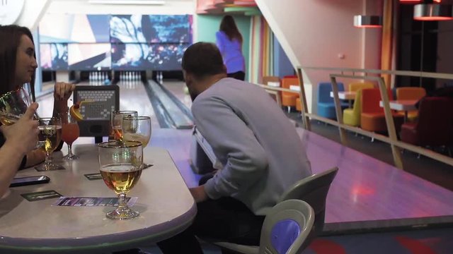 Friends playing and having fun at bowling game HD leisure video. Young man and woman rolling ball, cheers and drinks beer. Hobby and competitions