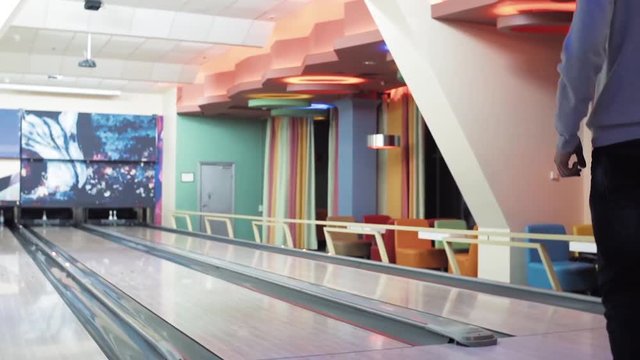 Young man playing bowling game and throwing ball to lane HD leisure video. Guy rolling ball on alley back view. Hobby and competitions