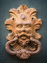 Golden door knocker of an old door in Italy.