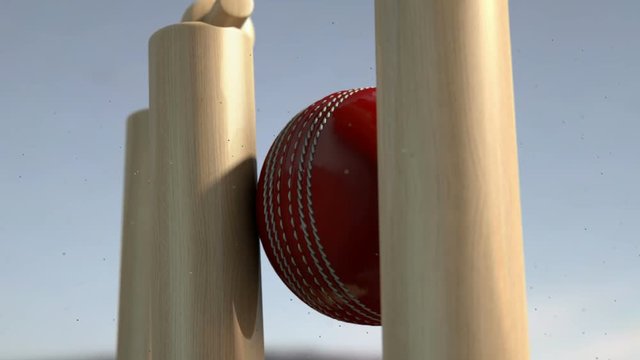 An ultra motion close up of a red leather stitched cricket ball hitting wooden wickets with dirt particles emanating from the impact in the day