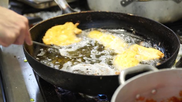 A female cook draining chicken cutlets from the oil, 4K