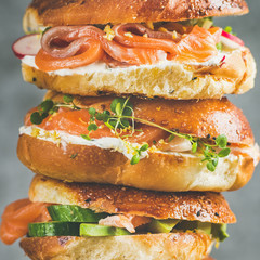 Close-up of of Bagels with salmon, eggs, vegetables, capers, fresh herbs and cream-cheese, grey concrete background, square crop. Healthy breakfast, lunch or take-away food concept