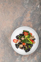 Wood ear mushroom stir-fry with ground meat and red peppers. Brown stone background. 